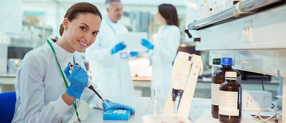 Woman in lab holding pipette above a tray