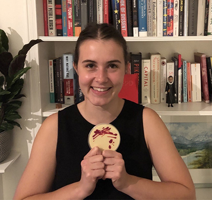 Female scientist displaying chocolate petri dish.