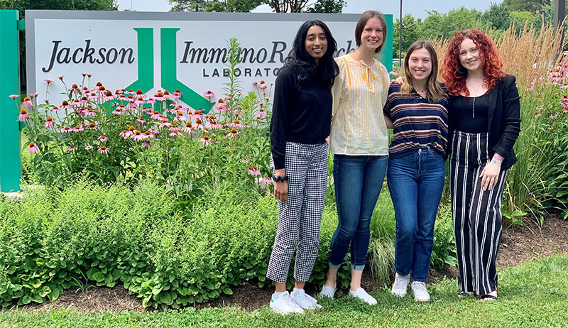 Group photo of 4 people in front of Jackson ImmunoResearch sign